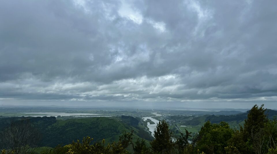 a view from a vantage point on a hike showing farmland and a cloudy sky