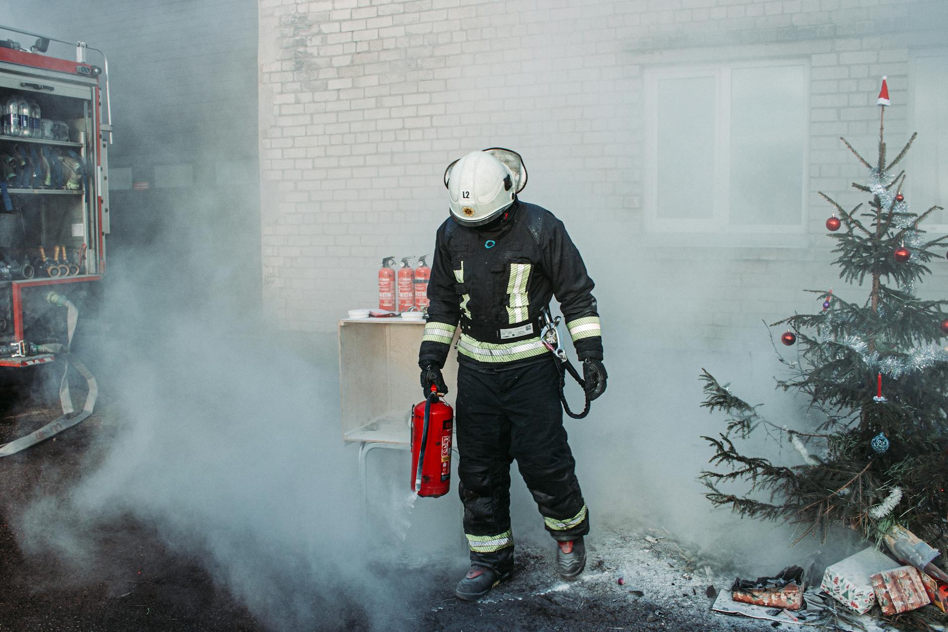 firefighter with extinguisher near christmas tree